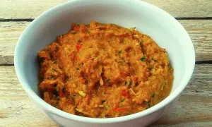 Miska z domową pastą curry o pomarańczowym kolorze, z widocznymi kawałkami warzyw i ziół.