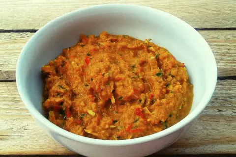 Miska z domową pastą curry o pomarańczowym kolorze, z widocznymi kawałkami warzyw i ziół.