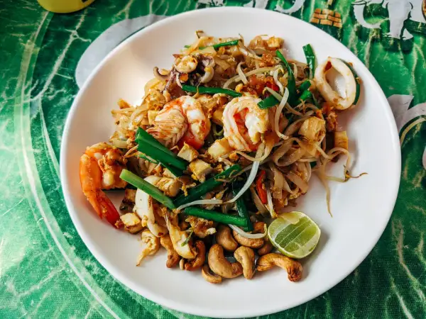 Talerz Pad Thai z krewetkami, kalmarami, kiełkami fasoli, orzechami nerkowca i limonką.