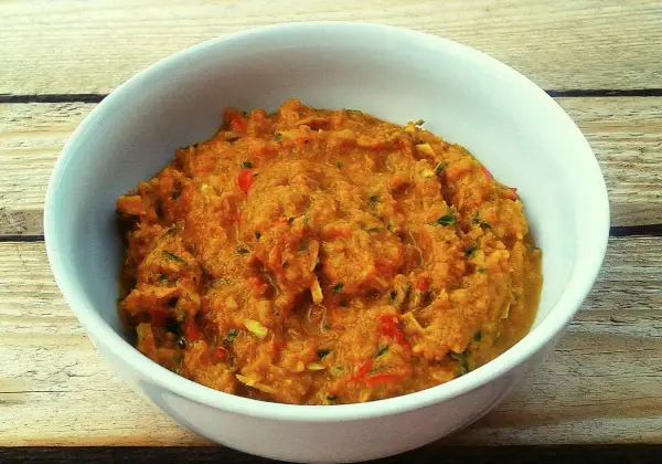 Miska z domową pastą curry o pomarańczowym kolorze, z widocznymi kawałkami warzyw i ziół.